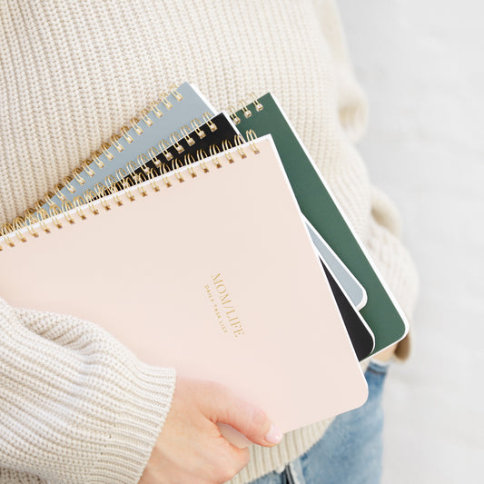 Stack of all spiral notebooks in pink, black, blue, green color ways