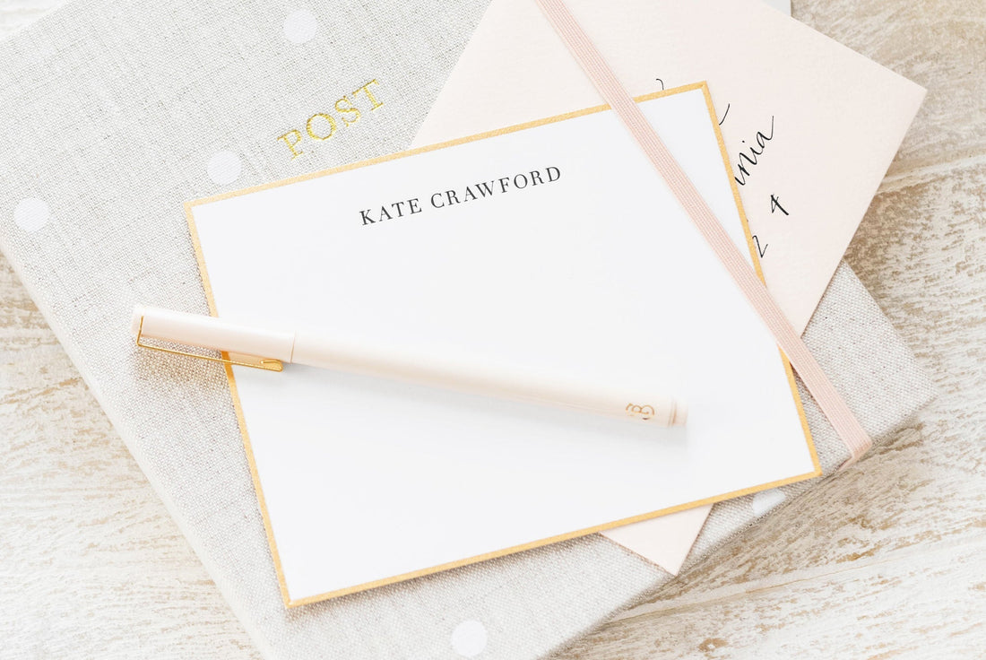 black and white custom stationery with gold hand painted bordered on top of an address book with a pen