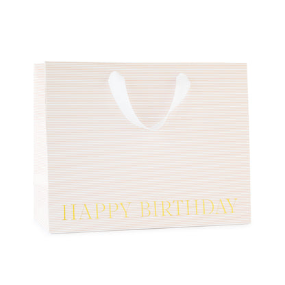 large gift bag with white ribbon handles with a pink stripe pattern printed with happy birthday in gold foil