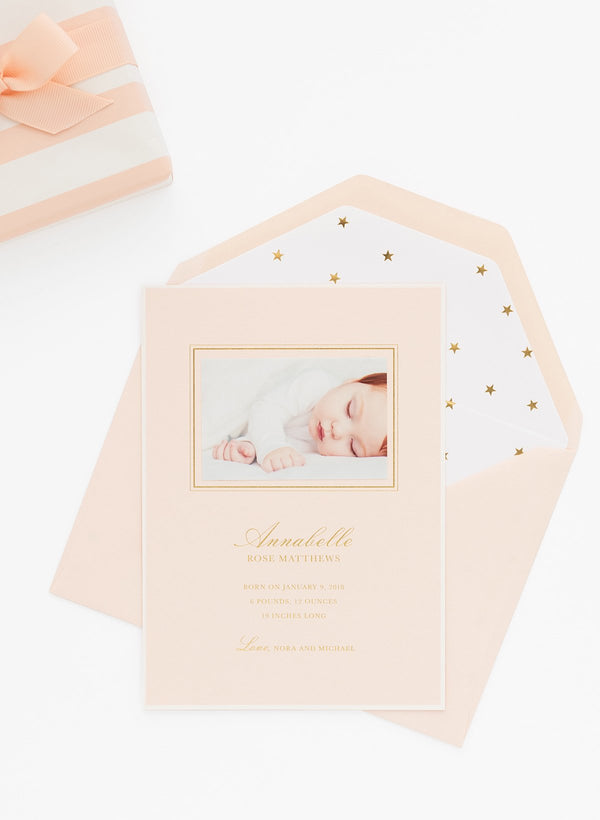 Pale pink birth announcement with a white and gold star envelope liner and a real photo of baby on it