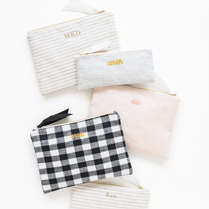 Assorted fabric pouches in stripe and check patterns with embroidered names and initials