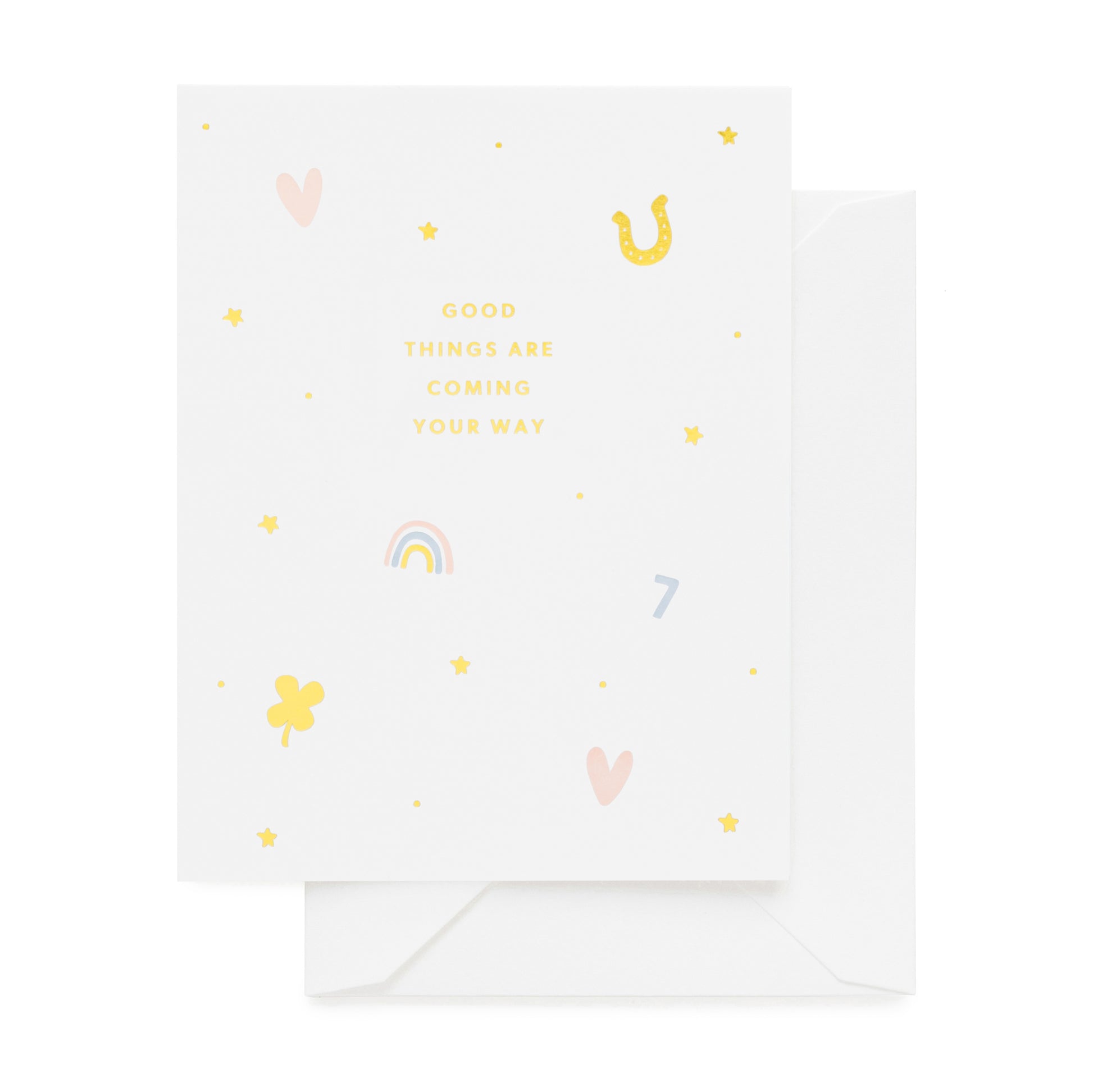 White greeting card with gold foil, pink, and blue icons in heart, horseshoe, rainbow, and lucky charm printed with 'good things are coming your way'