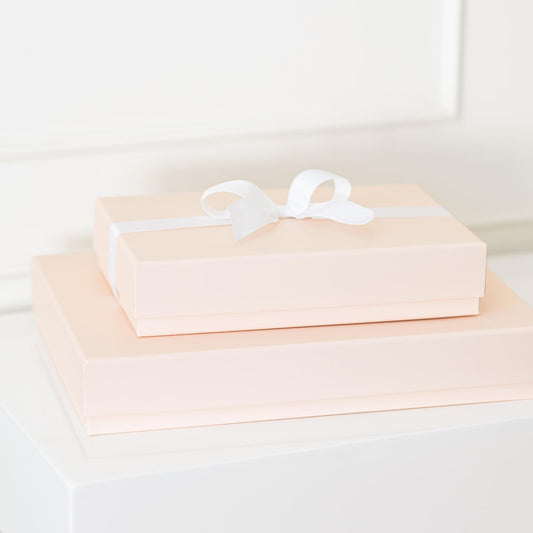 Stack of multiple sized pink gift boxes with white bow on top