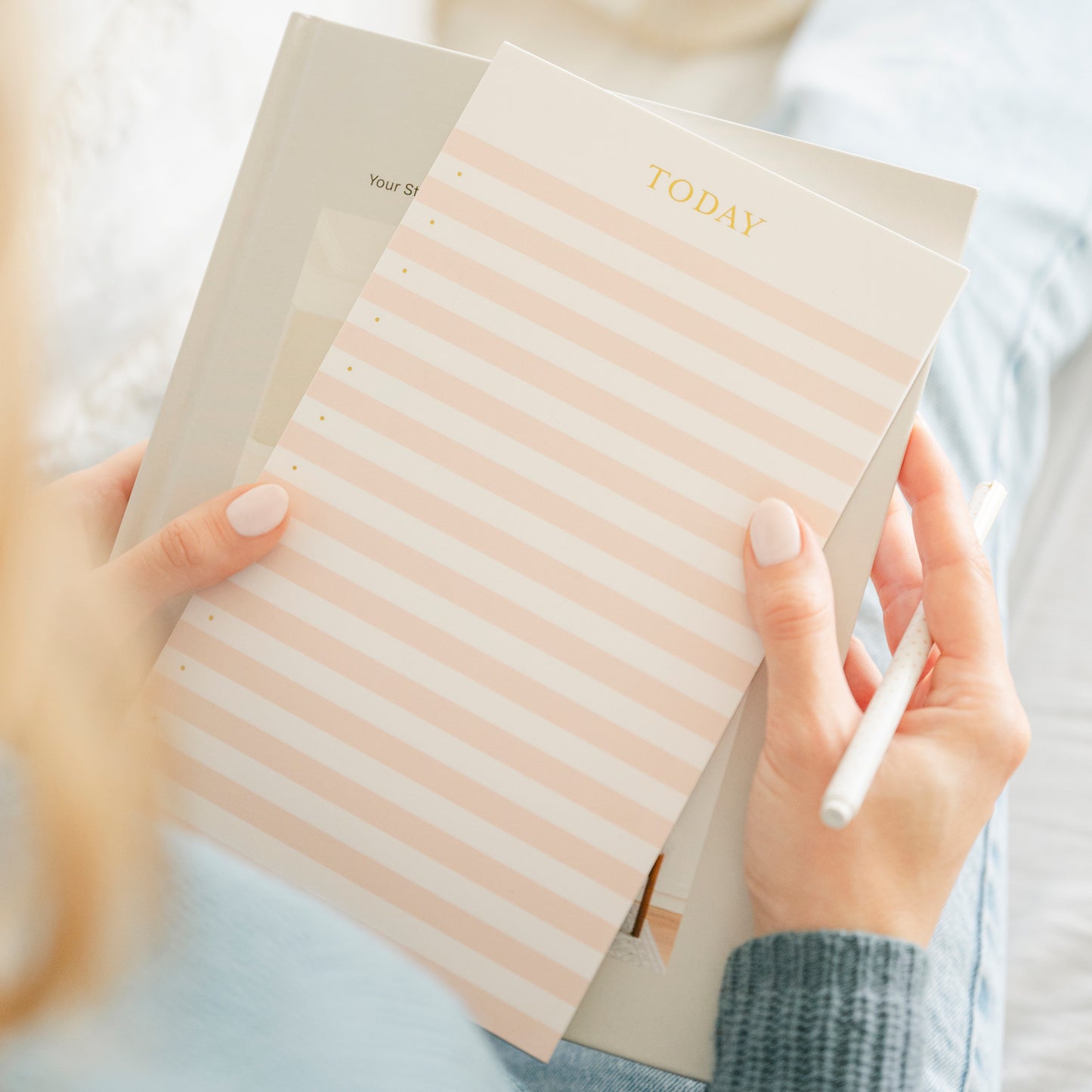 Pink and white striped today notepad in hand with a pen