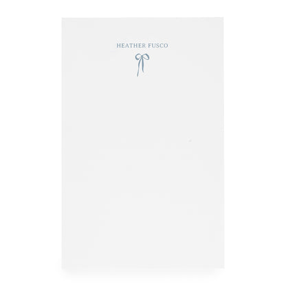 White notepad with ribbon bow and "heather fusco" in blue ink