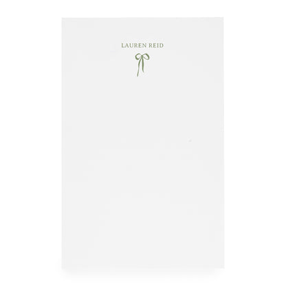 White notepad with ribbon bow and "lauren reid" in moss green ink