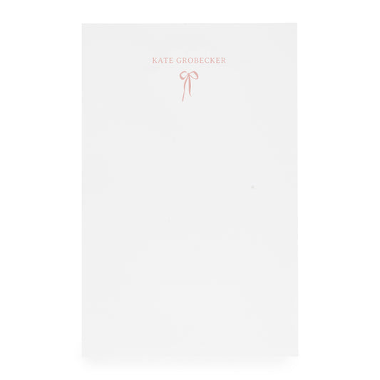 White notepad with pink bow and "kate grobecker" in pink