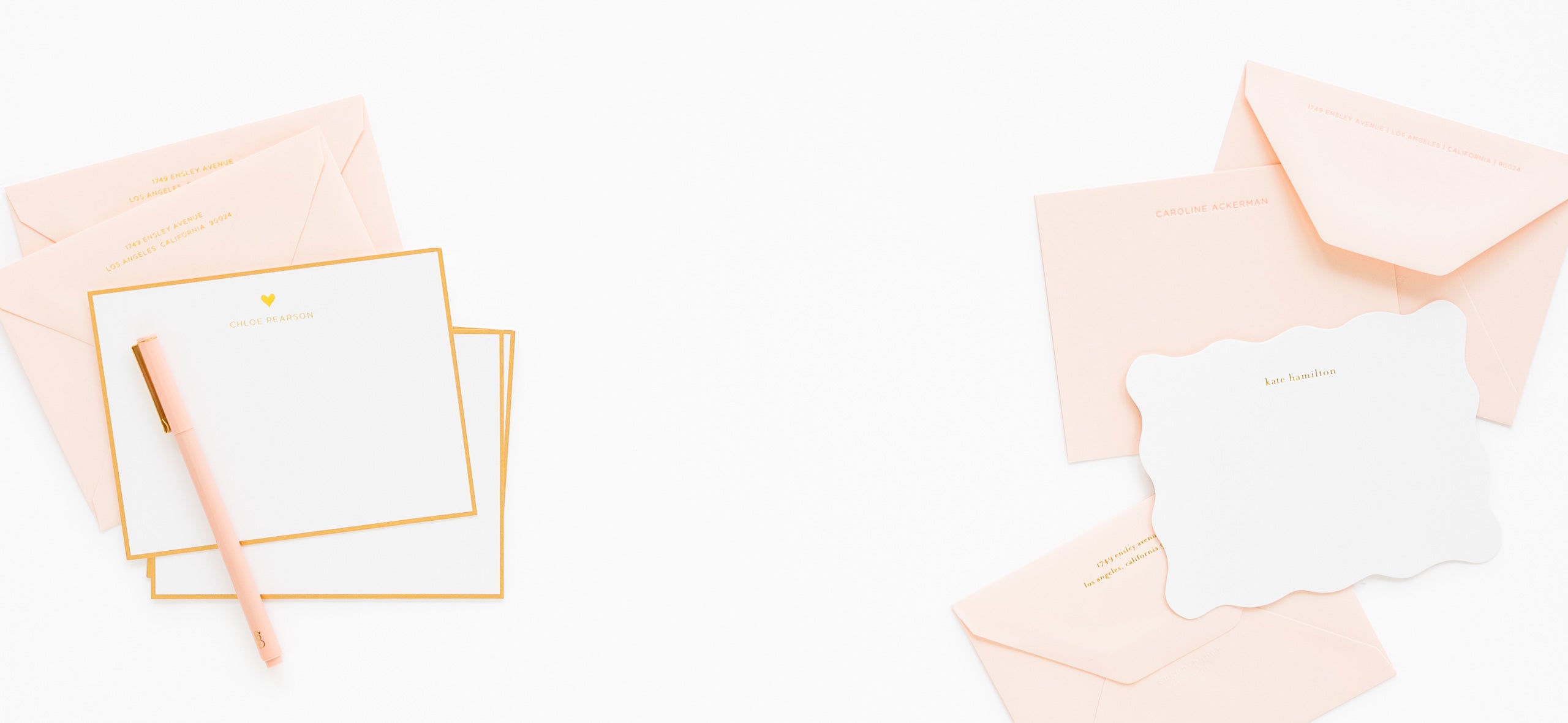 Stack of white cards letterpress printed with name with gold borders with pale pink envelopes