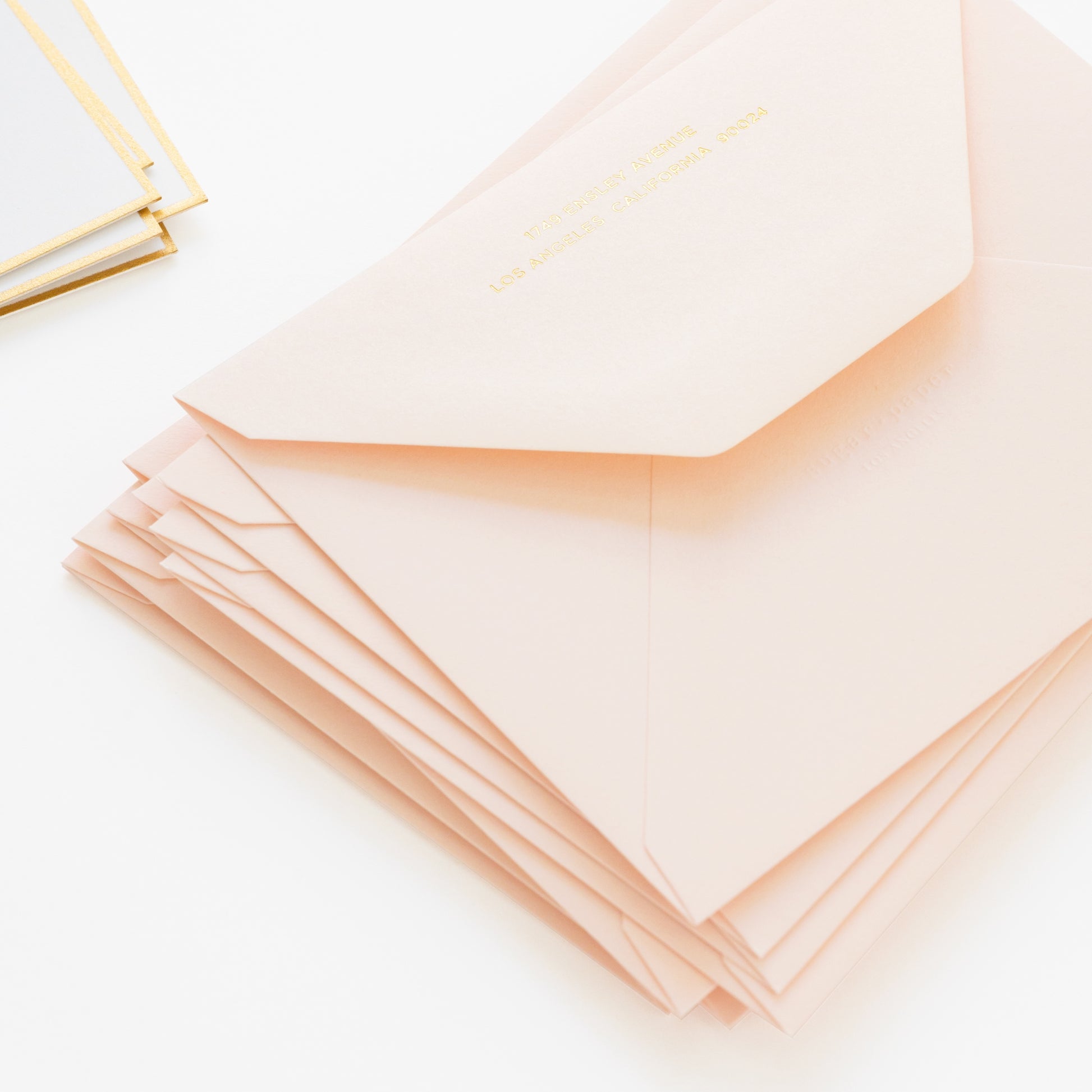 Stack of pale pink envelopes with sugar paper logo embossed