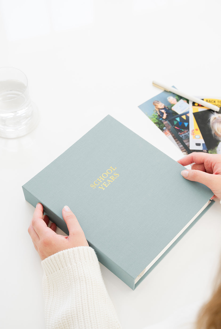 Person holding a blue keepsake book on a white surface.
