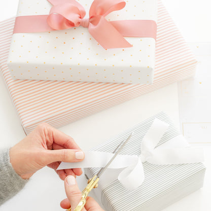 woman trimming ribbon on a gift with other wrapped gifts 