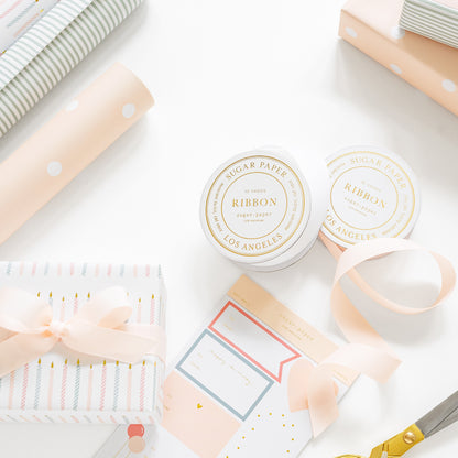 ribbon spools, gift tag stickers, and wrapping paper with a wrapped gift