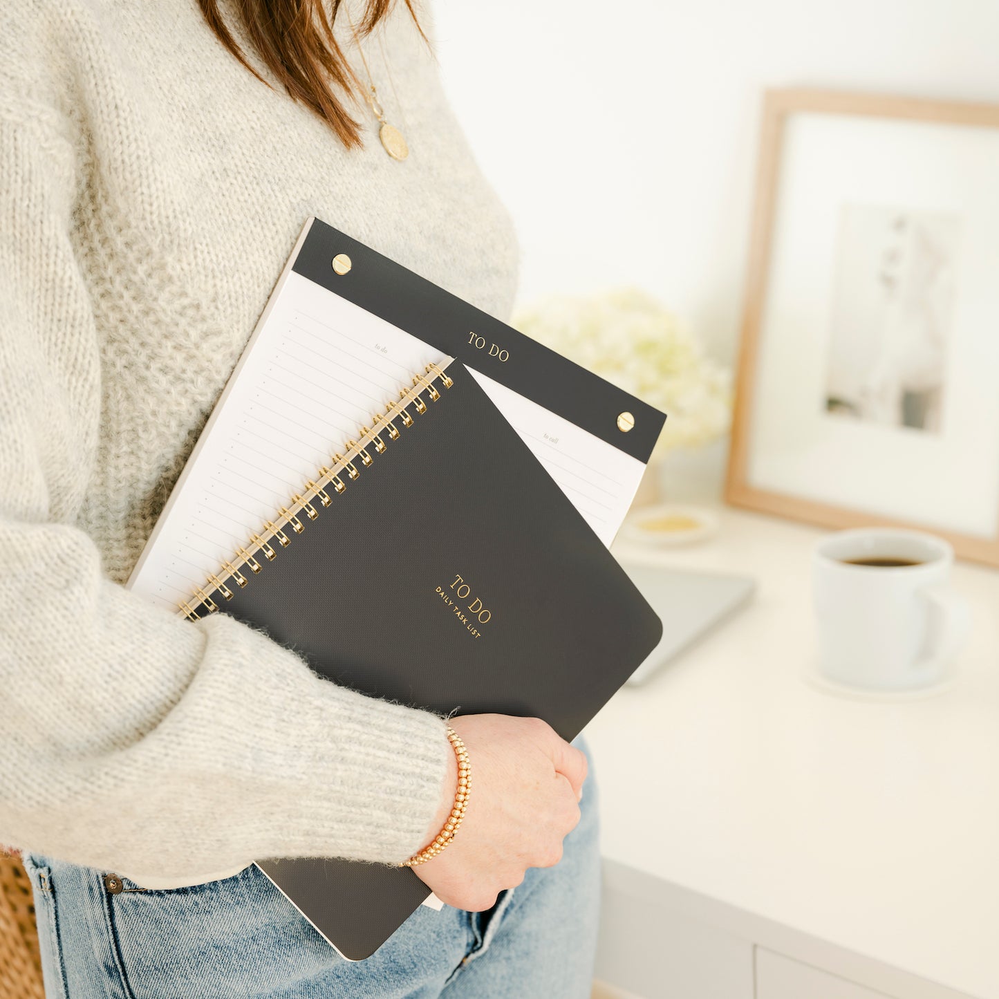 Stack of guided to do spiral notebook and to do notepad in black and gold colors