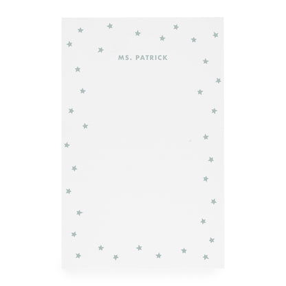 White notepad with scattered star border and 'ms. patrick' text in mint green ink