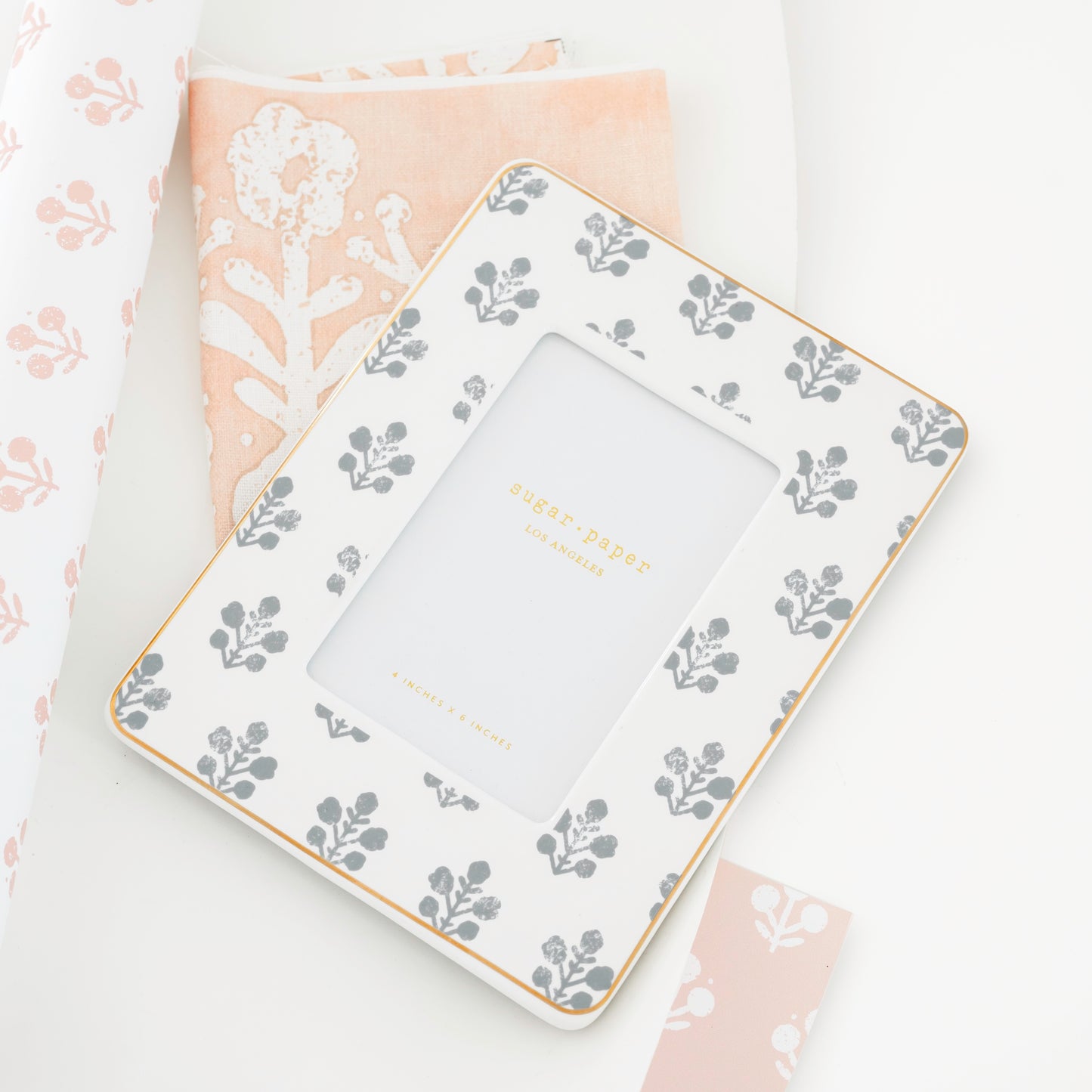 slate grey floral frame on top of floral pink and white fabric and wallpaper samples