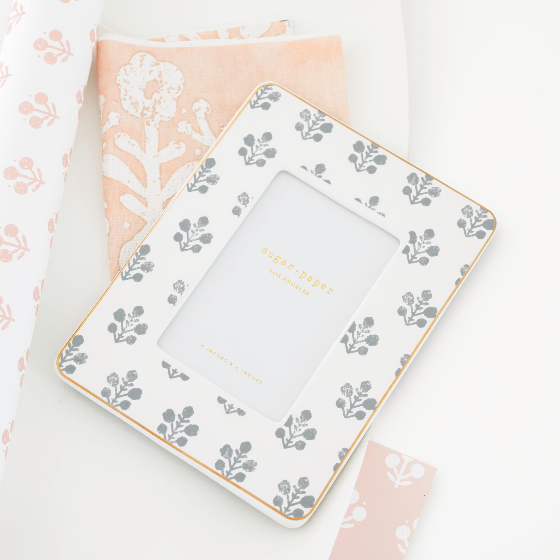 slate grey floral frame on top of floral pink and white fabric and wallpaper samples