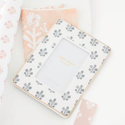 slate grey floral frame on top of floral pink and white fabric and wallpaper samples