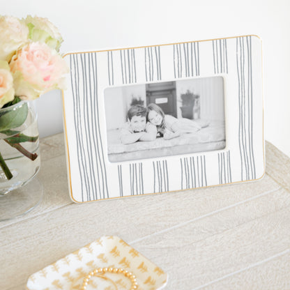 slate grey striped frame on bedside table with a photo of two kids and a yellow floral ceramic tray with jewelry