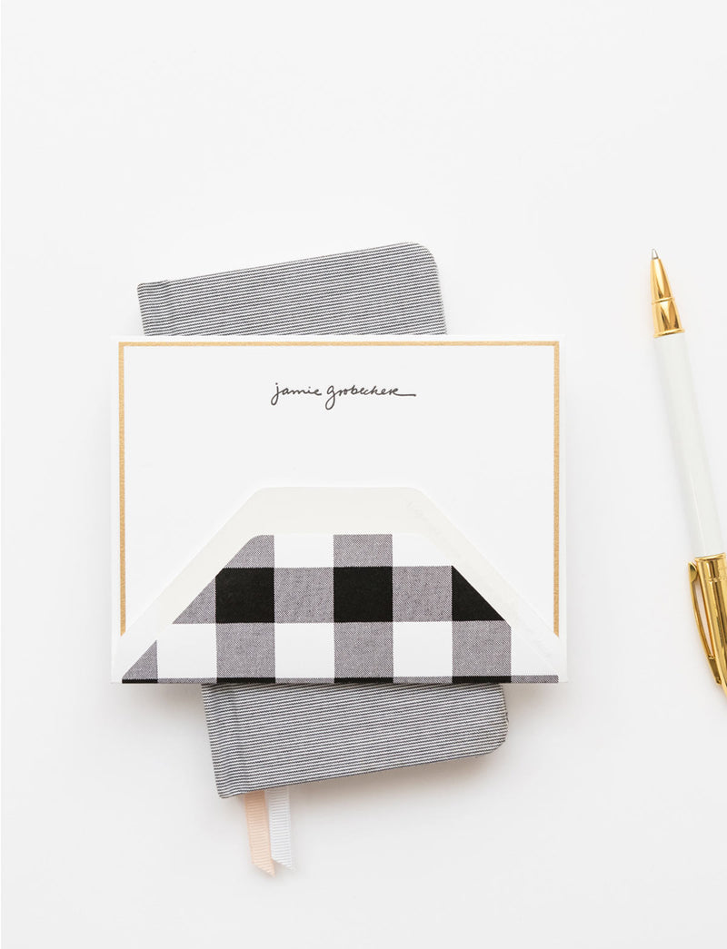 black hand lettered name letterpress printed on white paper with a gold border and a black gingham envelope liner