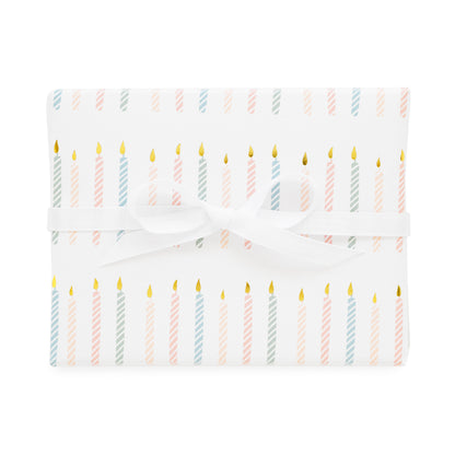 birthday candle gift wrap printed with a colorful candle pattern in pink and blue with gold foil tied with a white ribbon
