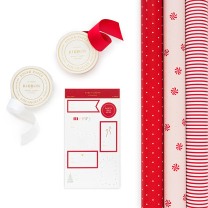 Wrapping paper kit including 3 rolls of wrap in red with white polka dots, pink with red and white peppermint candy and gold dots, and red and white stripe with rolls of red and white ribbon and holiday stickers