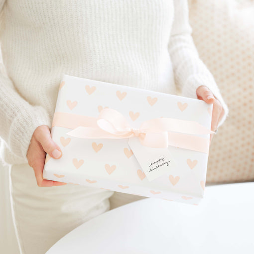 person holding a wrapped gift with a pink bow