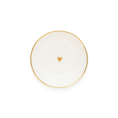 A white ceramic round trinket tray with gold details, including a gold heart in the center and a gold rim.